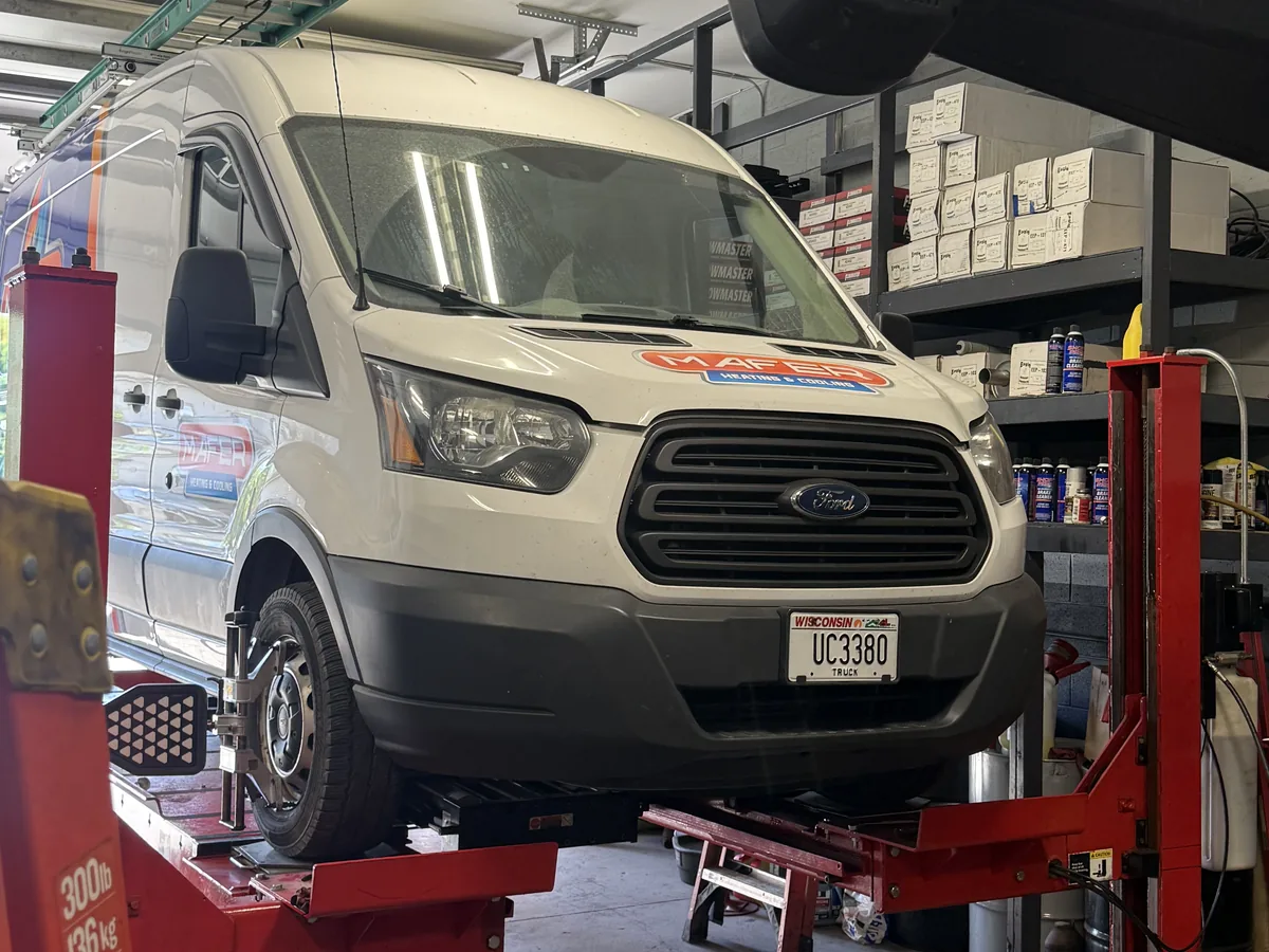 Cargo van raised on a wheel alignment rack inside the service bay