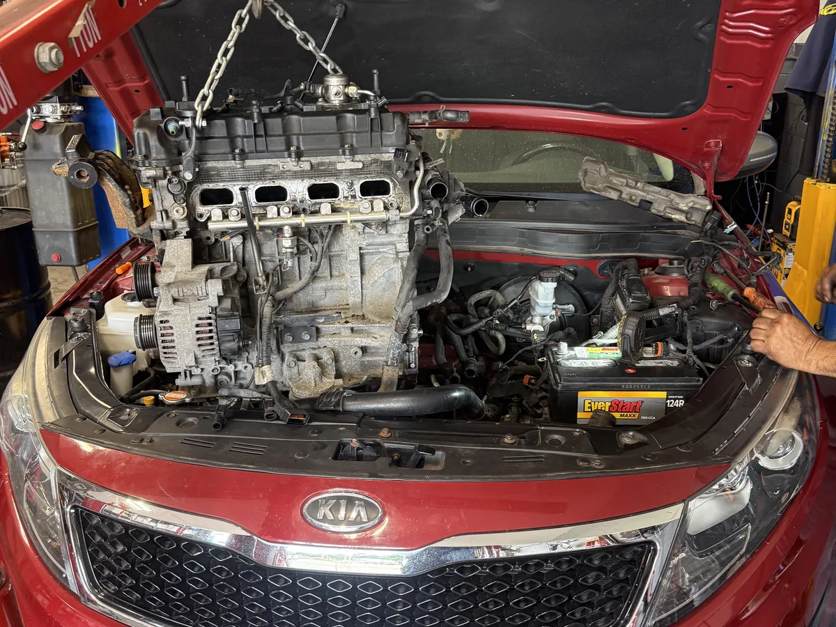 Engine lifted out of a sedan on a hoist during an engine replacement