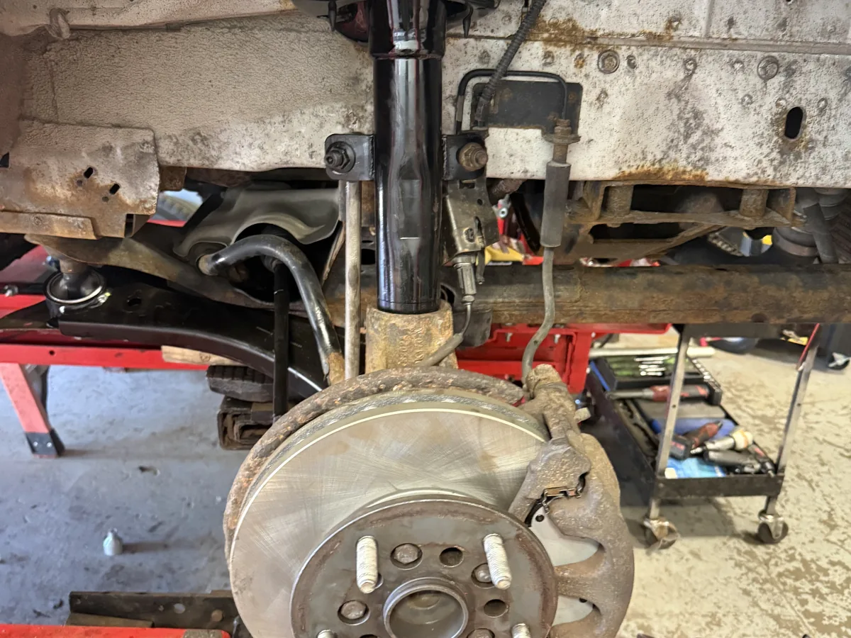 Corroded front strut and brake rotor before suspension service