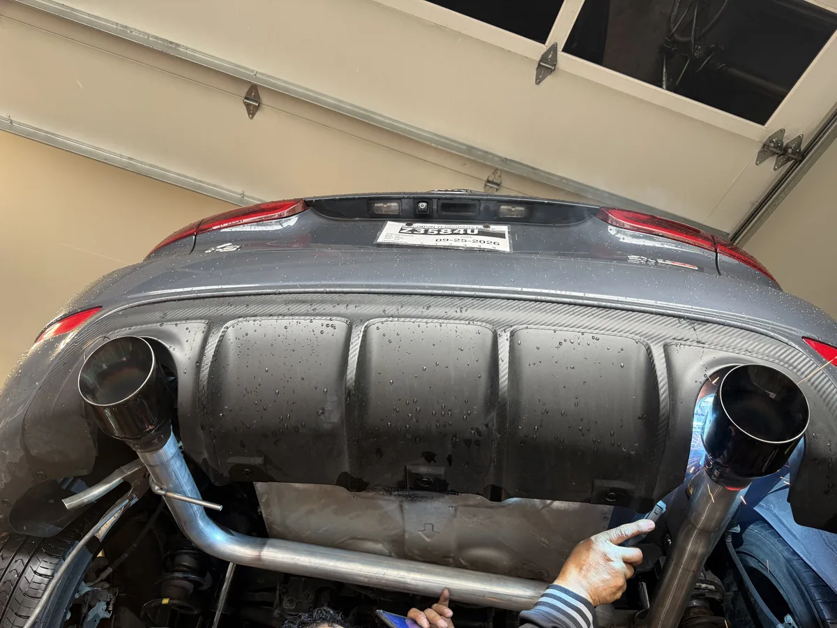 Our technician fitting a performance exhaust pipe under a sport sedan